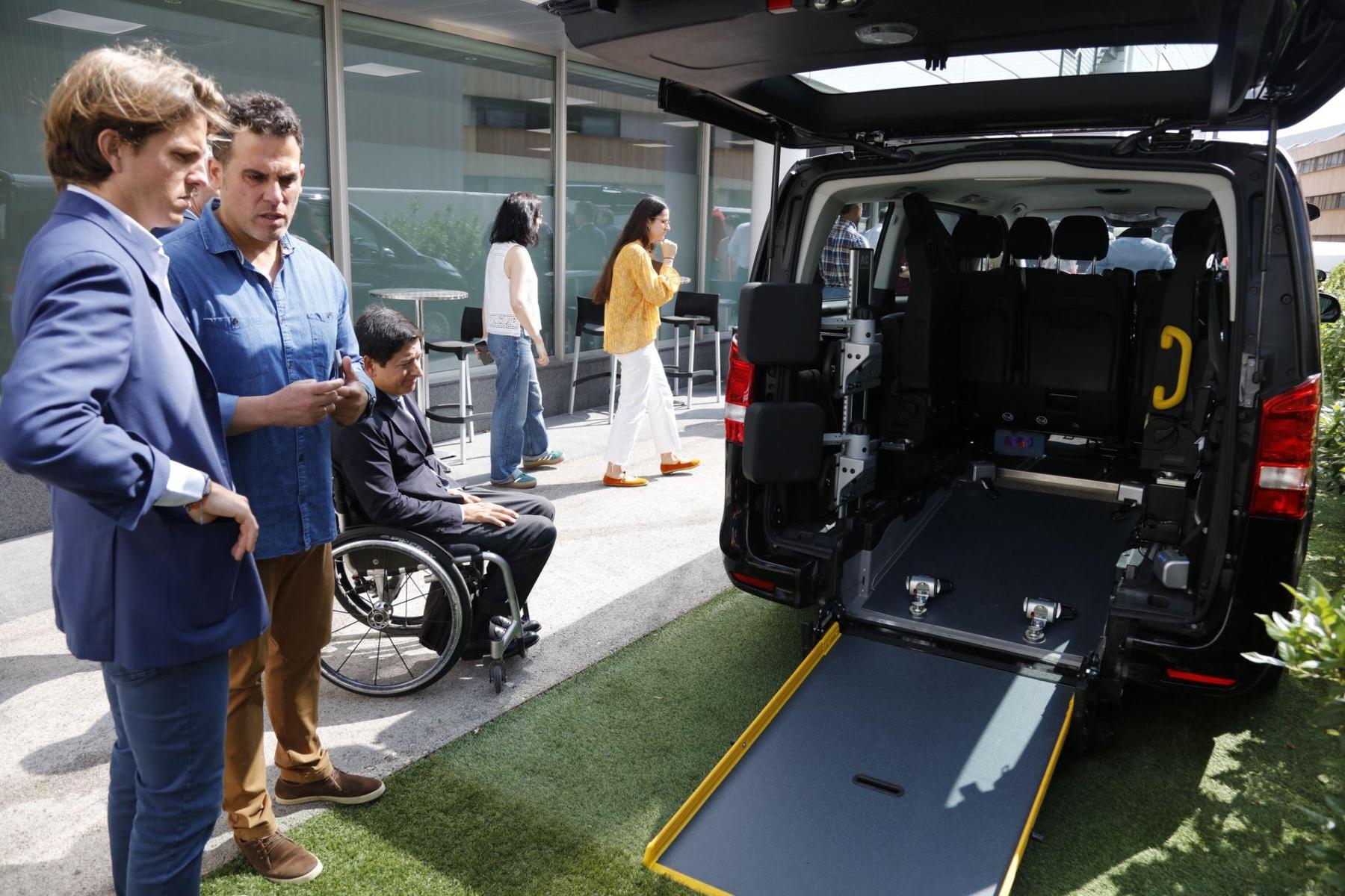 A Cabify Access adapted vehicle with its rear ramp deployed, while a wheelchair user and two colleagues look at it